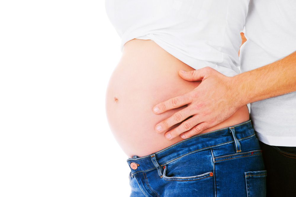 Primo piano di pancione di donna in gravidanza con mani del partner appogiate