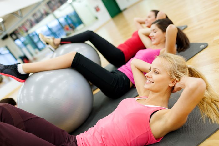 ragazze in palestra fanno esercizi per addominali con gambe appoggiate a fitball