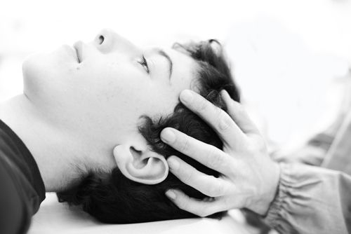 primo piano in bianco e nero di un ragazzo disteso durante una seduta di osteopatia