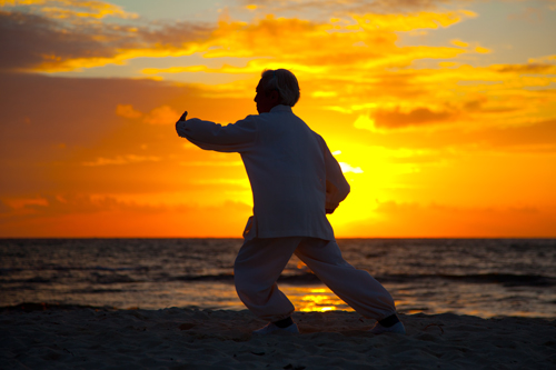 uomo pratica qi gong in spiaggia alla luce del tramonto